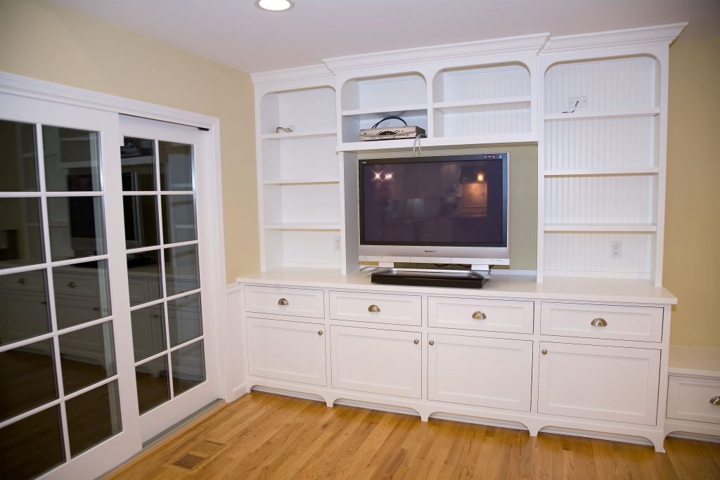 Staged living room furniture; Installed White TV hutch with silver TV and gold handles on drawers and doors